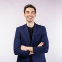 Portrait of young handsome businessman wearing suit standing with crossed arms with isolated on studio white background. Male smiling and looking at camera. Business and success concept.